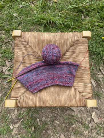Un bonnet laine fait main tricot présenté sur tabouret en paille