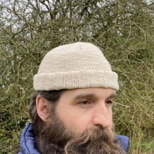 Bonnet docker beige en cachemire et coton porté par modèle, arbres à l'arrière fond, La laine de Galeine