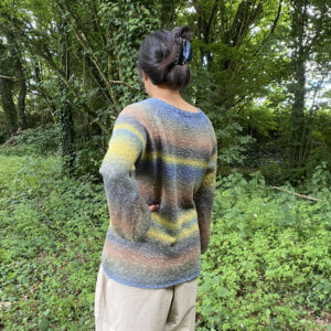 Pull en chanvre et coton multicolore, modelé par Steph, sur fond de végétation