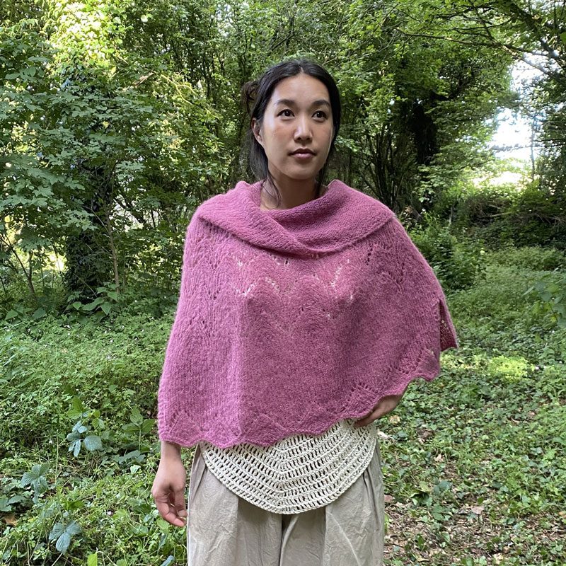 Poncho d'été rose, en alpaga et soie, présenté sur modèle, fond boisé, la laine de Galeine