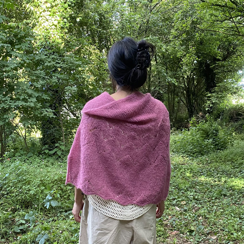 Poncho en alpaga et soie, couleur rose, présenté sur modèle, sur fond boisé, la laine de Galeine